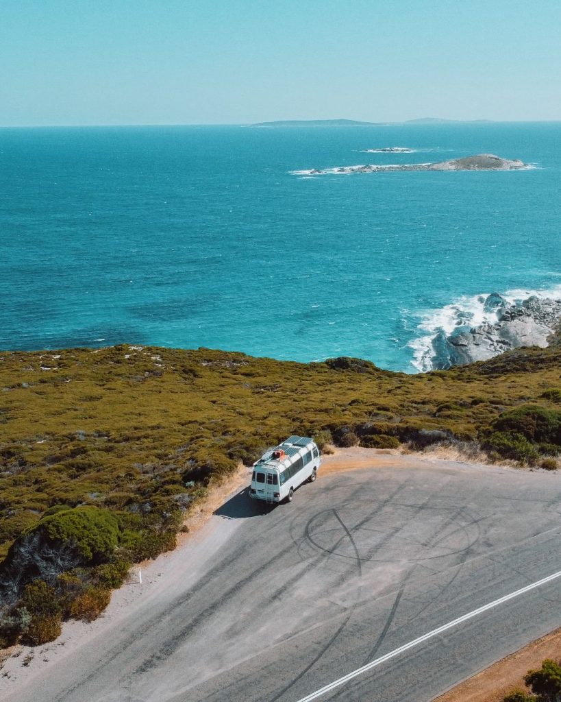 caravan bus parked on the side of the great ocean drive in esperance, western australia, overlooking the turqouise waters