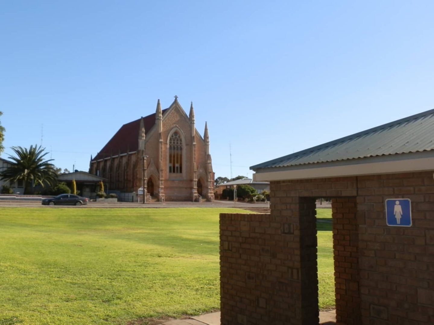Red-brick church with stained glass windows and public restrooms in the foreground, located in the town of Moonta on a Yorke Peninsula road trip.