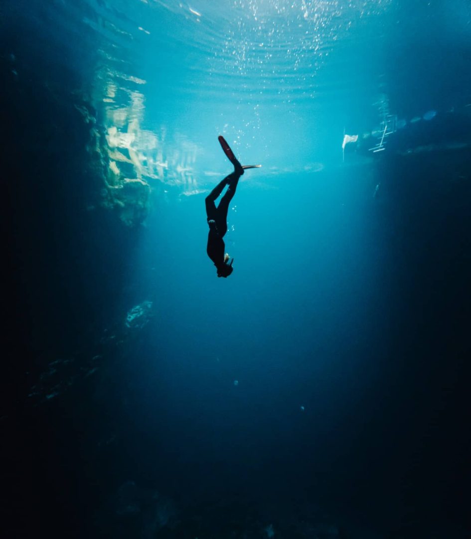 Freediver descends into the deep blue waters of Kilsby Sinkhole, a stunning freshwater dive site along the Melbourne to Perth road trip route.