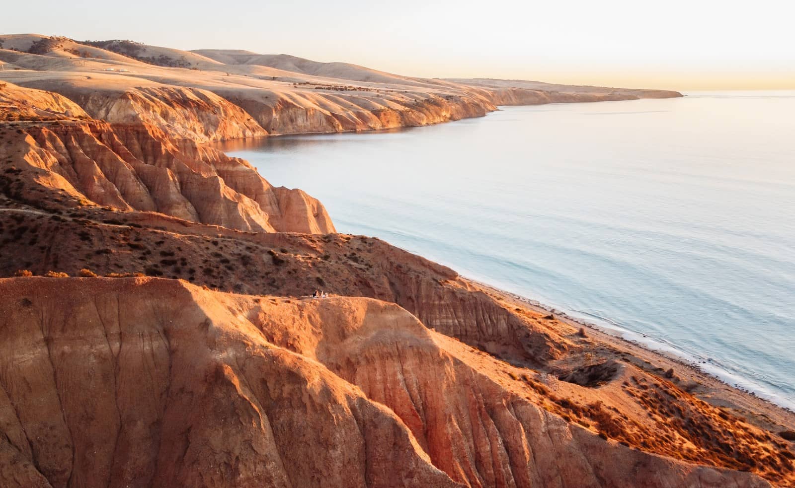 Golden cliffs at Sellicks Beach glow at sunset above a calm ocean, one of South Australia's coastal highlights on a Melbourne to Perth road trip.