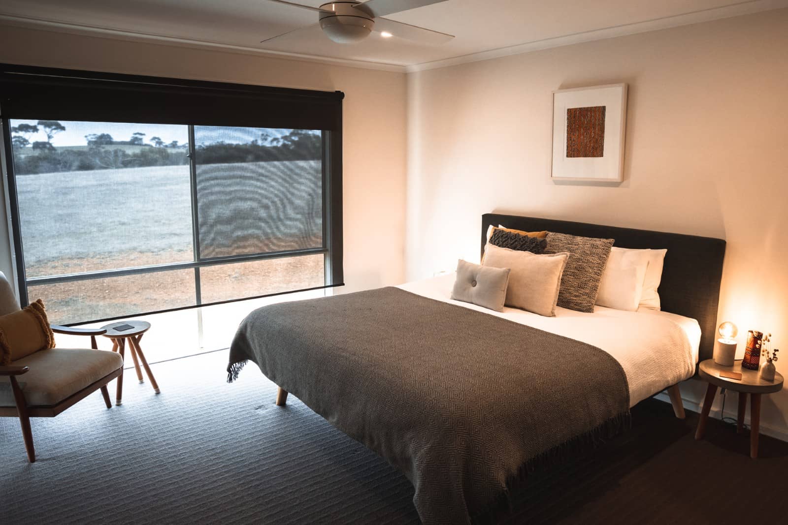 Stylish and cosy bedroom with a large bed, warm lighting and a view of open bushland through wide windows, perfect for a kangaroo island road trip 3 days stay.