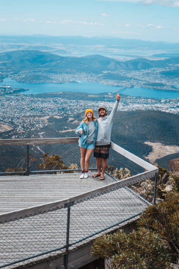 Couple standing on a lookout deck atop Mount Wellington with sweeping views over Hobart and the Derwent River, a scenic stop on the Tasmania East Coast Road Trip.