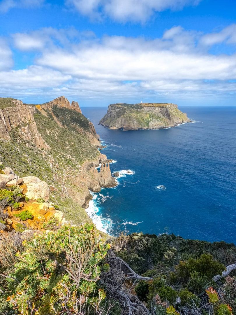 Tasman Island and dramatic coastal cliffs under blue skies, viewed from a lookout along the Three Capes Track on a 7 day Tasmania road trip.