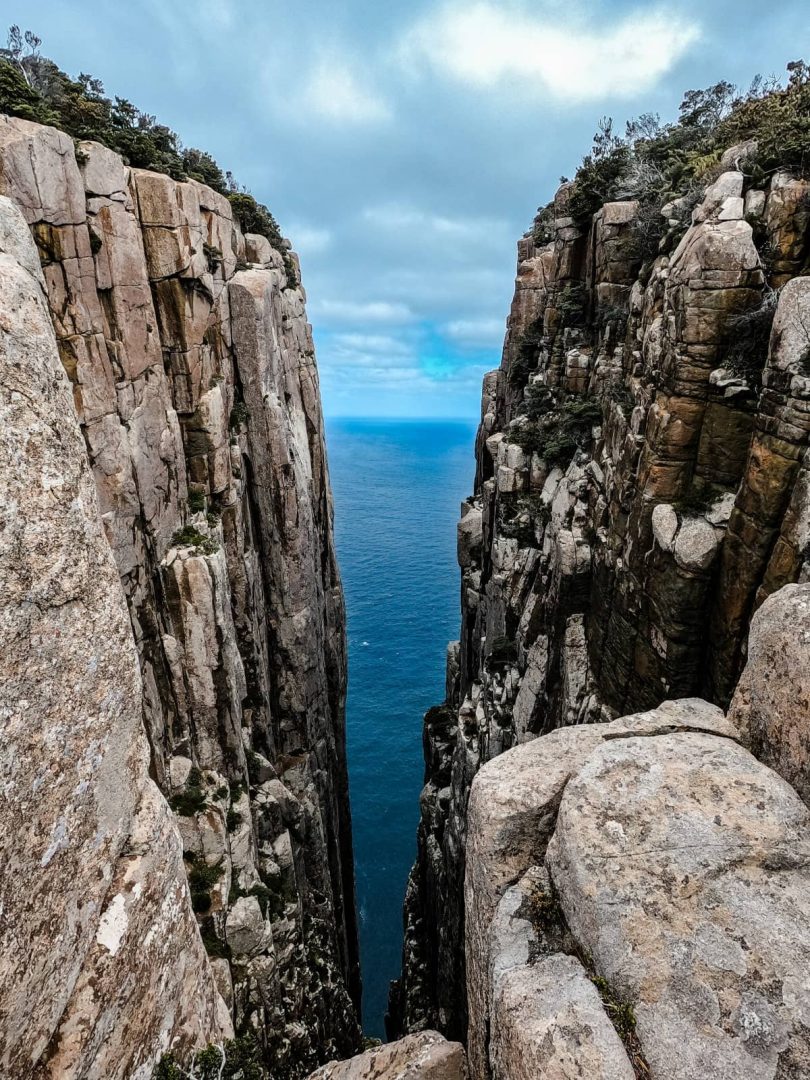 A narrow chasm known as "The Blade", between towering sea cliffs drops straight to the ocean below, a striking natural feature near Cape Pillar, on the Three Capes Track for free.