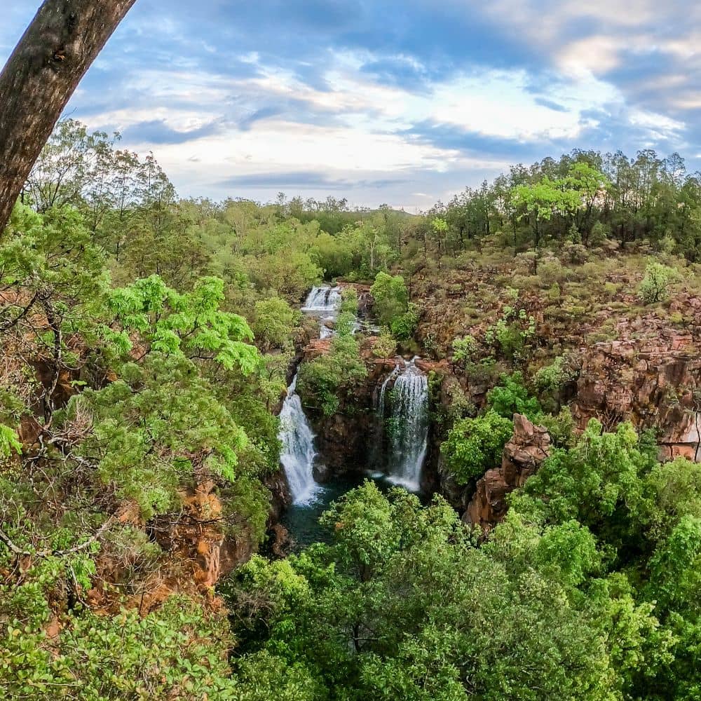 Three waterfalls flow into a body of water while surrounded by lots of greenery and trees. Part of the ultimate guide to Litchfield National Parks Walks. This is the popular Florence Falls in the Northern Territory.