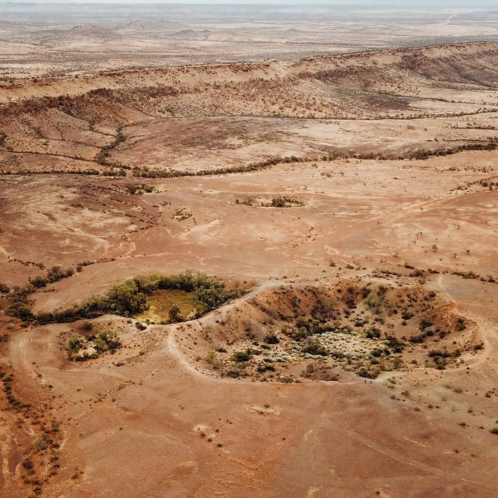 A rippled red sand dune against a clear blue sky, taken near Uluru