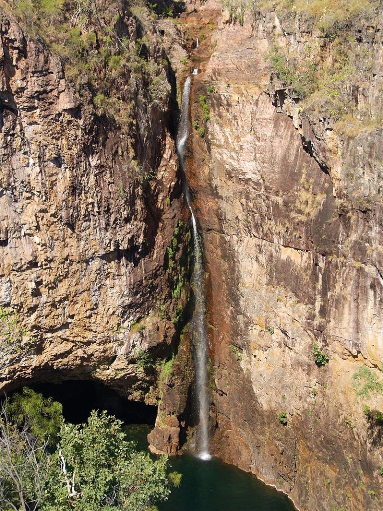 Tolmer Falls seen from above, the massive waterfall drops into a rockpool, surrounded by rock surface and some trees.