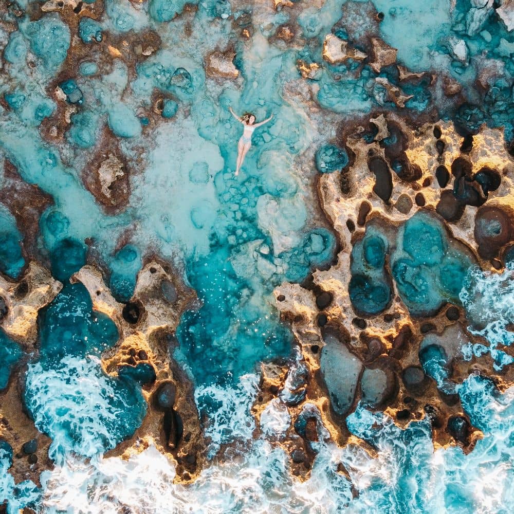 Drone shot of a lady lying in rock pools of coconut wells. Broome, Australia