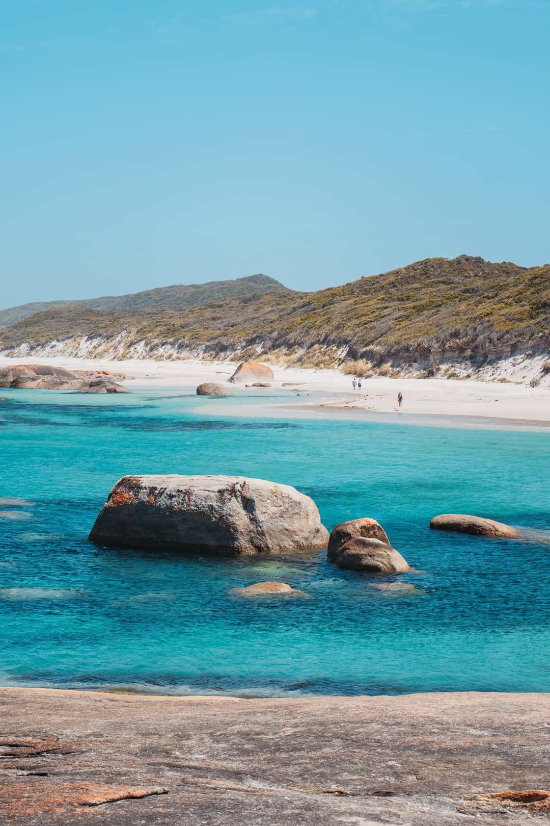 a view of Greens Pool Western Australia with turquoise water and, rock formations, white sand shore, majestic mountain, and blue sky