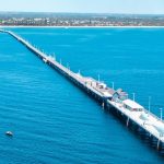 The iconic Busselton Jetty stretches into the turquoise waters of the Indian Ocean, a landmark pier known as the longest wooden jetty in the world, located in the coastal town of Busselton, Western Australia.