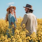 Chris and Bec standing in a field of yellow flowers under a clear blue sky. It shows the best time to visit Perth Western Australia