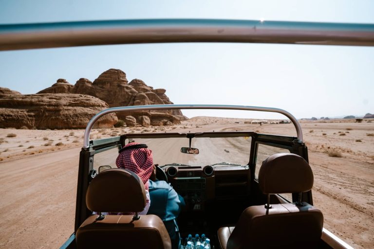 A local guide drives through AlUla’s rocky desert in a 4x4 vehicle, passing sandstone formations—a must-have desert excursion on a saudi arabia itinerary.