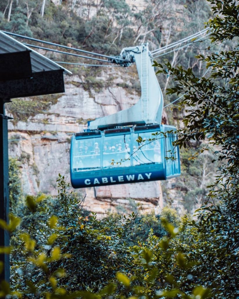 A blue Scenic World cableway glides above the Blue Mountains forest, offering a unique aerial view—one of the iconic things to do in the Blue Mountains.