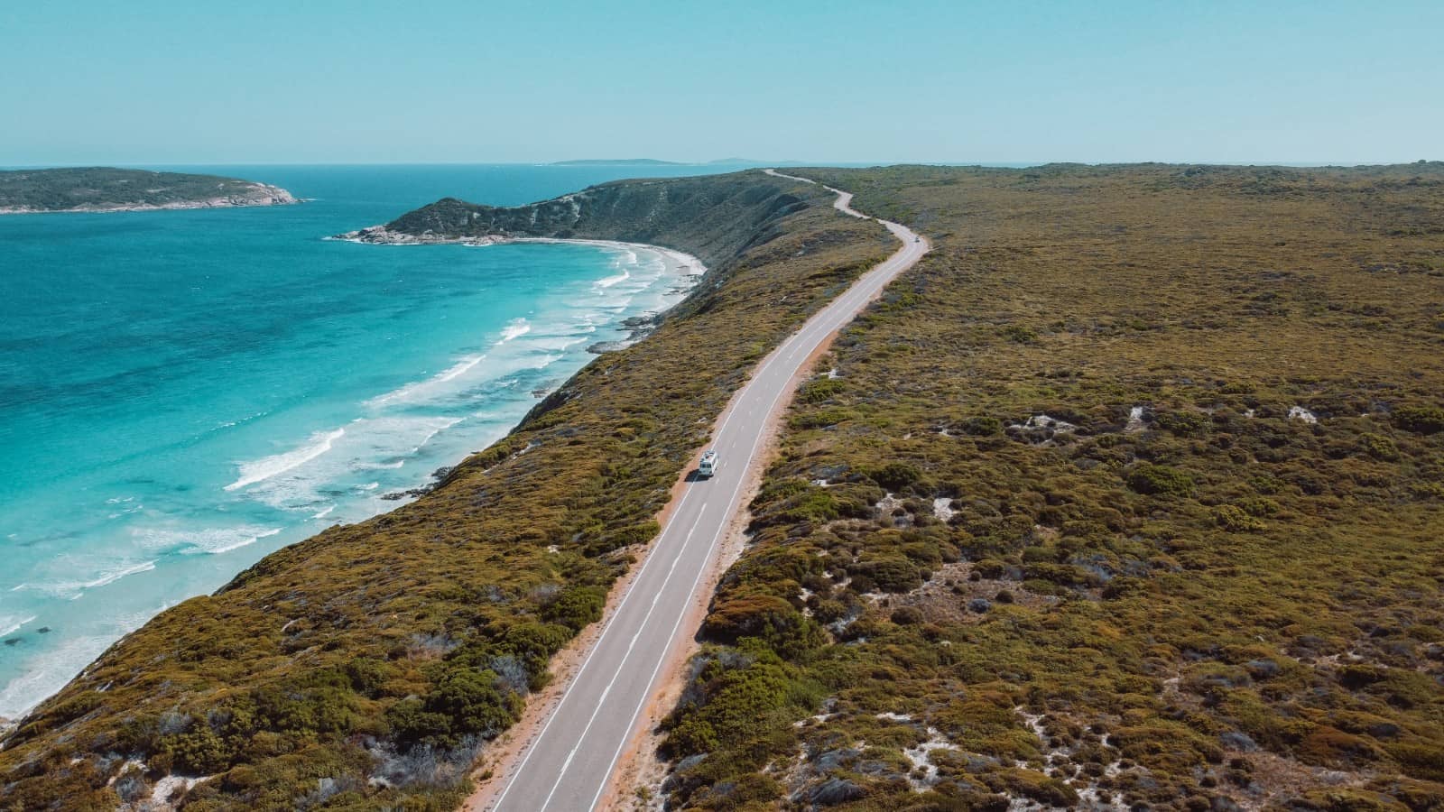 A drone shot of a winding coastal road near Esperance, Western Australia, with turquoise waters on one side and bushland on the other, ideal for scenic road trips in Australia.