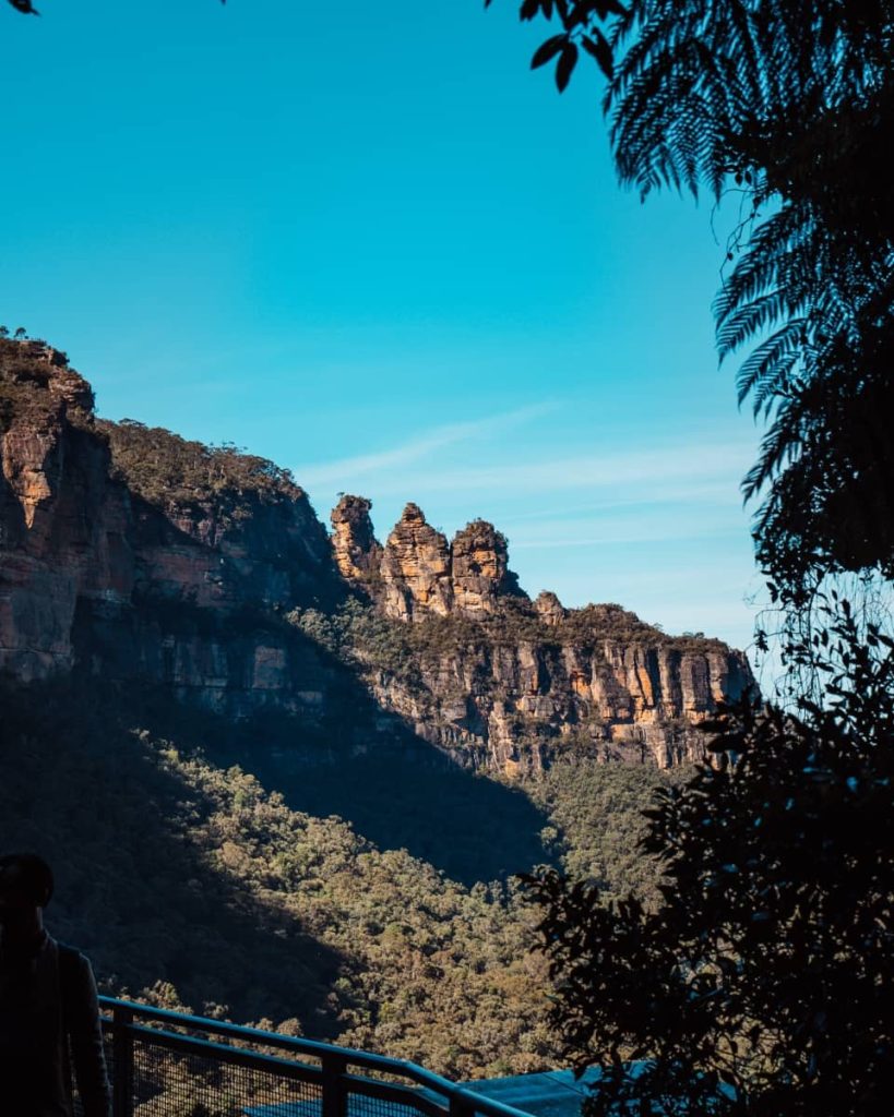 View of the Three Sisters rock formations from a scenic lookout platform surrounded by forest in the Blue Mountains, NSW.