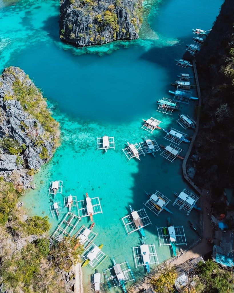Aerial view of traditional bangka boats in the bright blue waters near Kayangan Lake, showcasing the beauty of Coron, Philippines and popular things to do there.