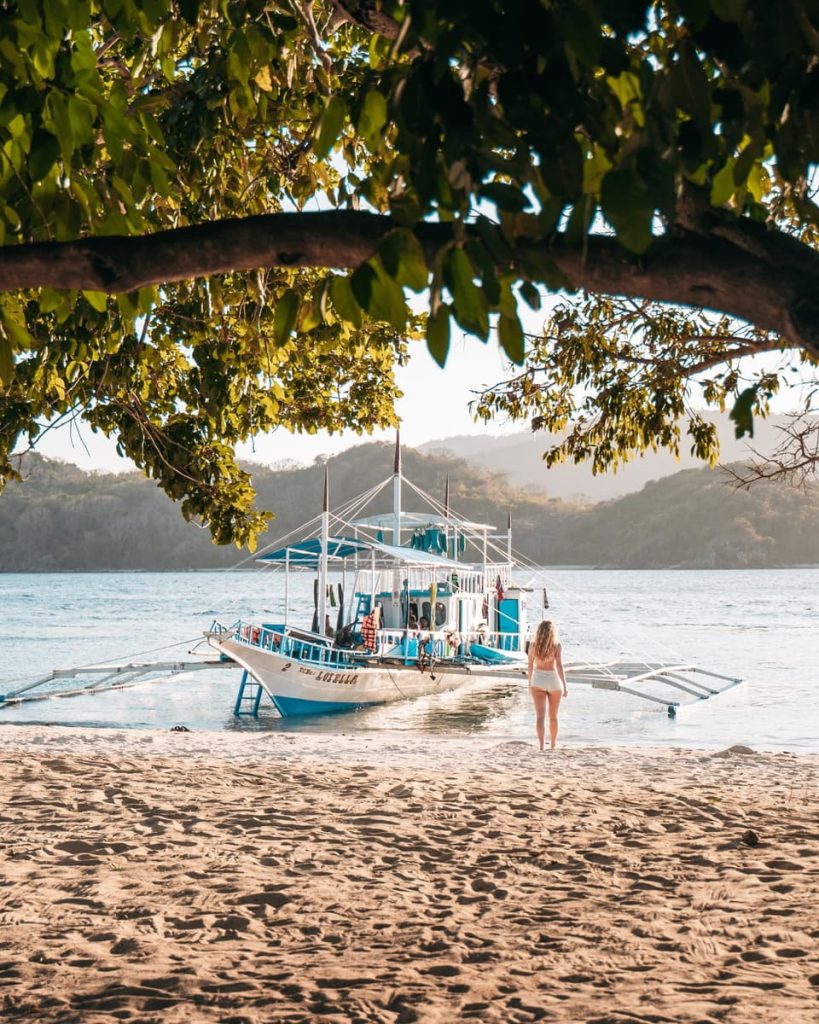 Woman walking toward a traditional outrigger boat during a Keeloma Island hopping tour, one of the most relaxing things to do in Coron, Philippines.
