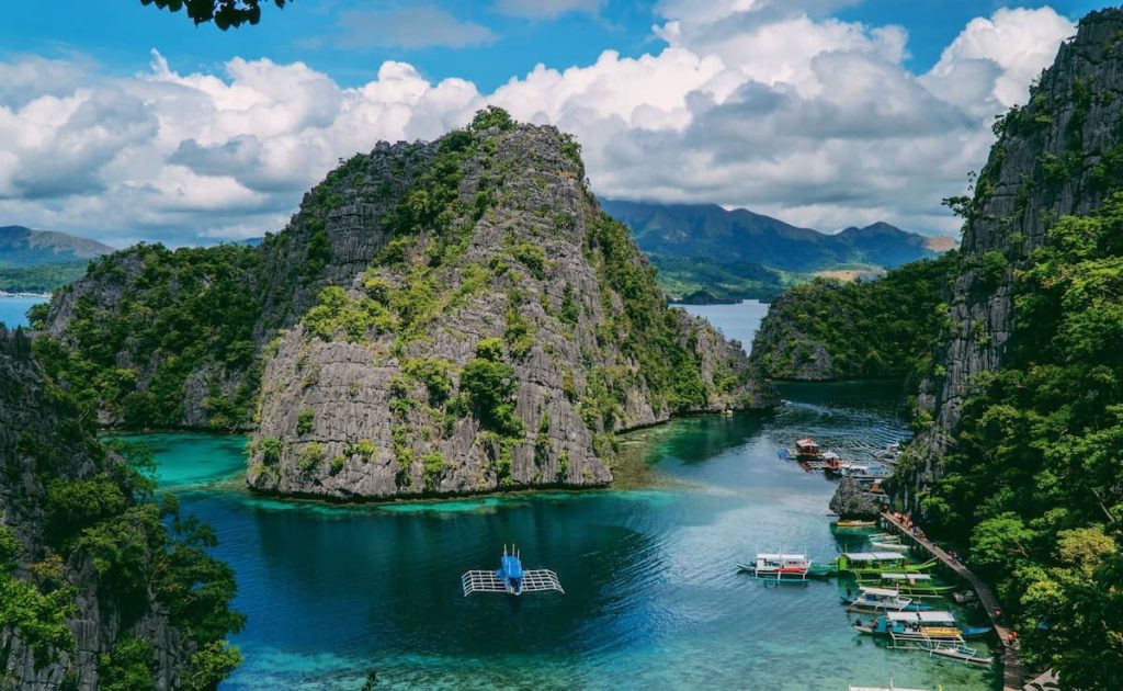 View of limestone cliffs and vibrant blue water at Siete Pecados Marine Park, one of the most scenic things to do in Coron, Philippines.