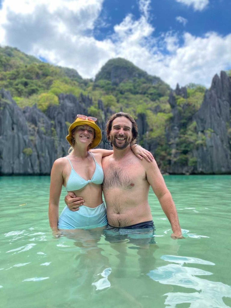 Chris and Bec smiling in the shallow turquoise waters of Hidden Beach in El Nido