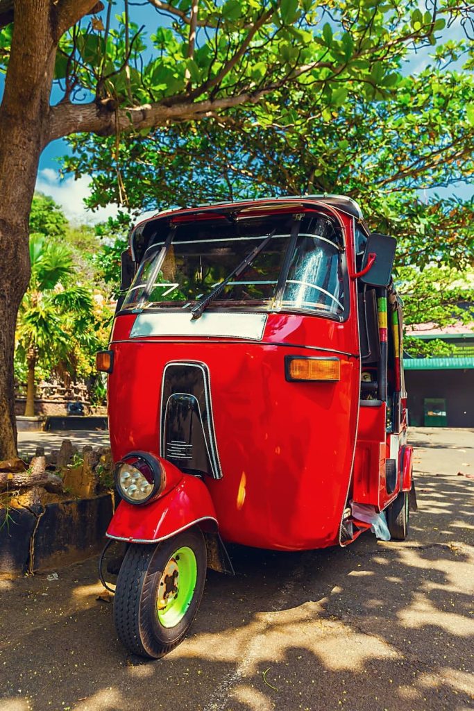 Bright red tuk-tuk taxi parked under a tree in Coron, Palawan—riding one is one of the fun and local things to do in Coron, Philippines.