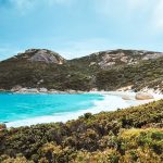 A vibrant turquoise bay framed by green hills and smooth granite boulders in South West Australia. This coastal scene captures the natural beauty found along a south west australia road trip 7 days itinerary.