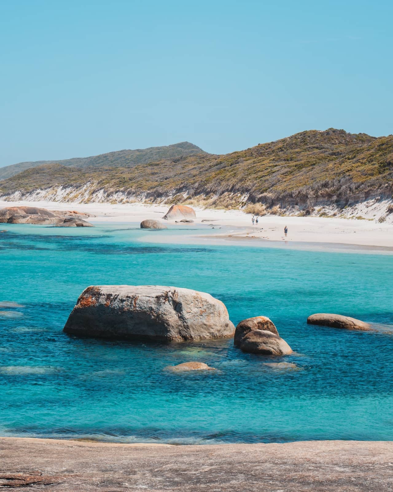 Clear blue waters meet bright white sand with scattered boulders on Greens Pool, Denmark, Western Australia. Remote coastal gems like this are perfect for a south west australia road trip 7 days.