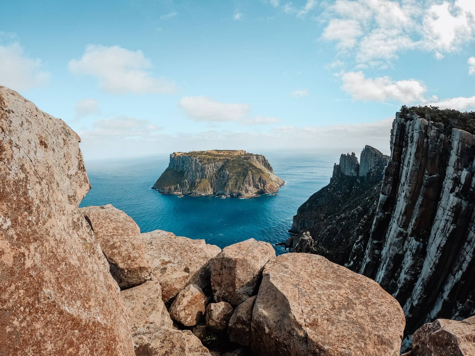 Dramatic view of Tasman Island from high sea cliffs, with layered rock formations in the foreground and deep blue waters below, showcasing one of the top things to do in Tasmania for nature lovers and hikers.