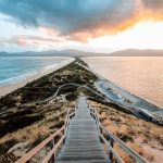 Wooden staircase of Truganini Lookout leading down to The Neck on Bruny Island at sunset, with narrow land connecting two parts of the island between the ocean and bay, one of the most iconic things to do in Tasmania.